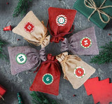  advent calendar with numbered drawstring bags on a textured surface with Christmas decorations.