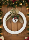 Decorative wreath with a bell and greenery on a textured surface