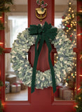 Wreath made of green and gray textured material on a red door background