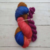 Two skeins of colourful yarn tied together on a wooden surface