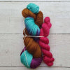 Two skeins of colourful yarn tied together on a wooden surface