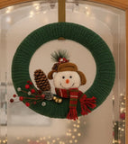 Green knitted wreath with a snowman decoration on a white background