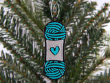 Decorative ornament shaped like a skein of yarn with a heart on a Christmas tree.